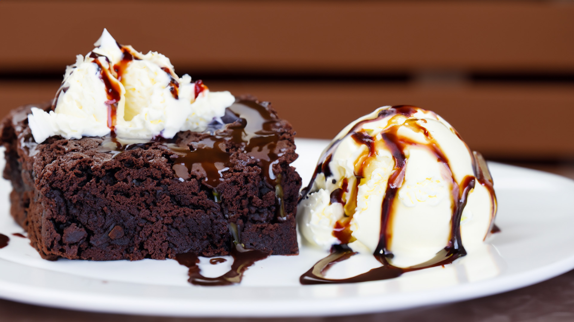 Chocolate brownies topped with vanilla ice cream, whipped cream, chocolate syrup, and garnishings.